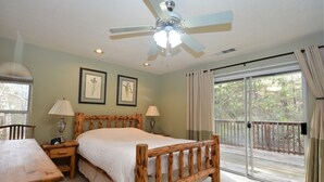 A bedroom with a wooden bed, two bedside lamps, a ceiling fan, and a large window with a view of trees. - Walter Lake Area, Gated Community with Pool (Bass Lake)