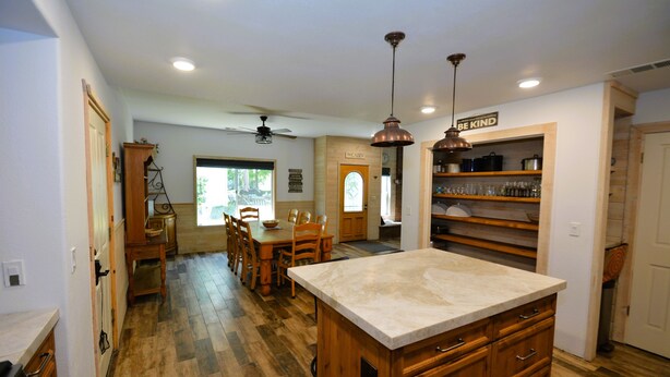 A kitchen with wooden cabinets, a marble countertop, and a ceiling fan. - Walter Lake Area, Gated Community with Pool (Bass Lake)