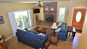 A living room with a fireplace, a blue sofa, a coffee table, and a television mounted on the wall.