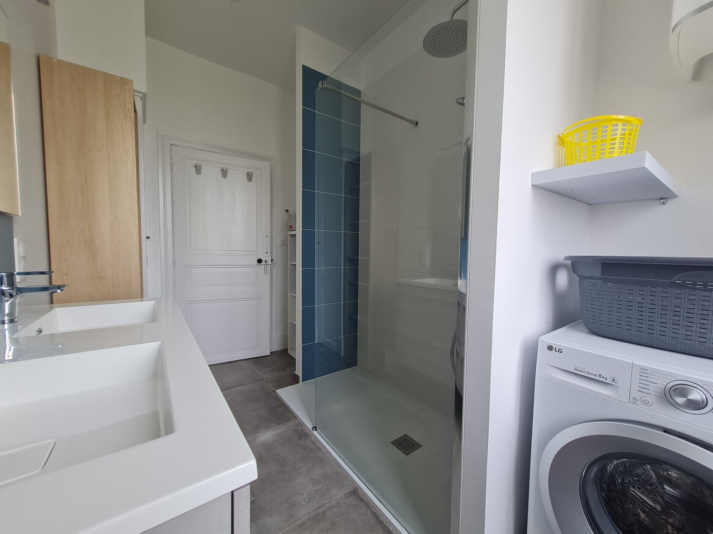 A modern bathroom with a glass-enclosed shower, a white sink, and a laundry machine.