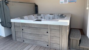 A hot tub with a wooden exterior and a control panel, located in a room with a wooden floor and a ceiling with exposed beams. - 19th Century House with Heated Pool, Spa, and Close to Beaches (La Garnache)