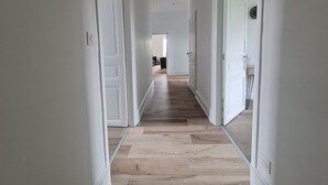 A hallway with white walls and wooden flooring leading to a room with a door. - 19th Century House with Heated Pool, Spa, and Close to Beaches (La Garnache)