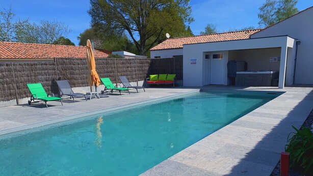 A rectangular swimming pool with a tiled deck, surrounded by lounge chairs and a covered area with a satellite dish. - 19th Century House with Heated Pool, Spa, and Close to Beaches (La Garnache)