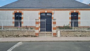 A building with a dark blue door, white picket fence, and a stone foundation. - 19th Century House with Heated Pool, Spa, and Close to Beaches (La Garnache)