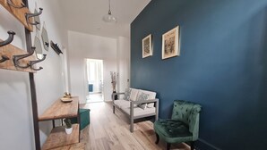 A modern living room with a sofa, a green armchair, and a dining area with a wooden table and chairs. - 19th Century House with Heated Pool, Spa, and Close to Beaches (La Garnache)