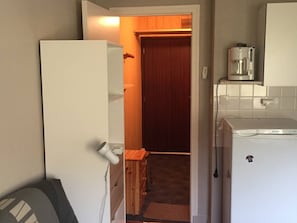 A compact kitchen with a refrigerator, coffee maker, and a wooden cabinet.