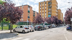 A street lined with parked cars and multi-story residential buildings.