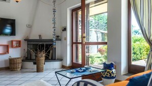 Un salon avec une cheminée, un téléviseur et une grande fenêtre avec des rideaux.