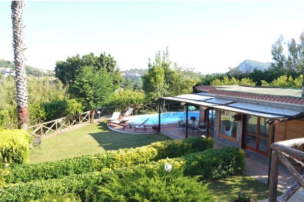 Un espace piscine avec des chaises longues, un patio couvert et une vue sur une montagne.