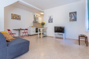 Un salon moderne avec un canapé, un téléviseur et un coin cuisine.