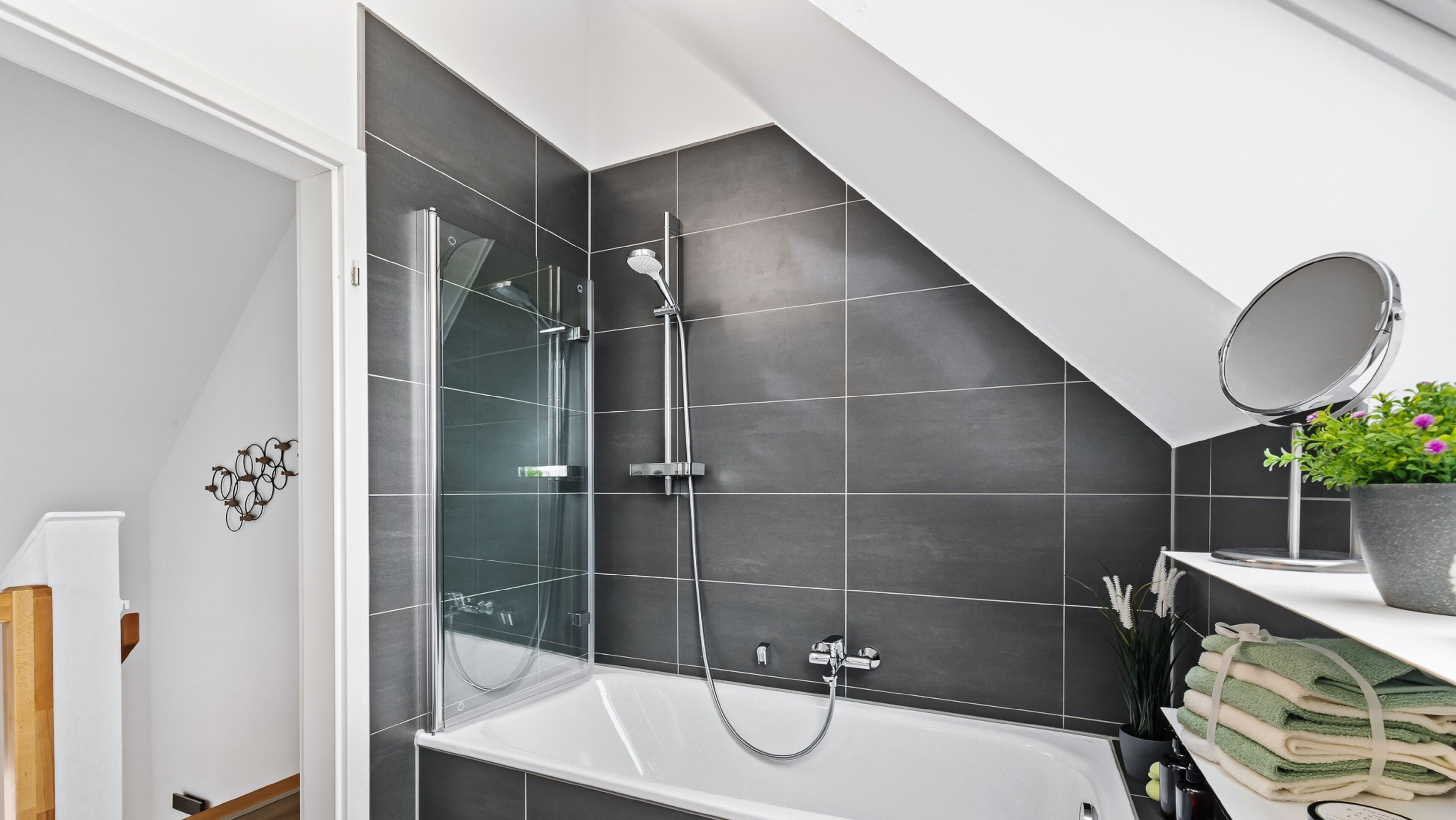 Une salle de bain moderne dotée d’une douche à parois de verre, d’une baignoire sur pieds et d’un meuble-lavabo agrémenté d’un miroir et d’une plante en pot.