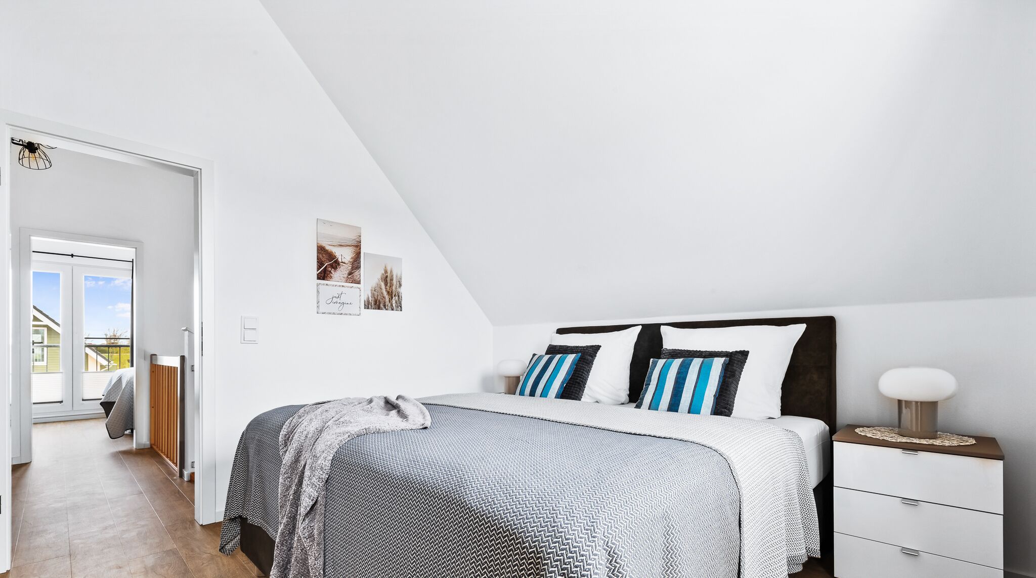 Ein Schlafzimmer mit Bett, Nachttisch und Kommode. Ein Fenster bietet Blick ins Freie.