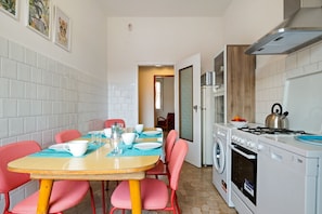 A compact kitchen with a washing machine, a stove, and a dining area with a table and chairs.