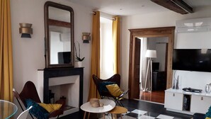 Un salon moderne avec une cheminée, un téléviseur et un coin repas doté d’une table en verre.