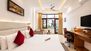 Une chambre d’hôtel avec un grand lit, un bureau, une chaise, une télévision et une fenêtre avec des rideaux.