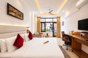 A hotel room with a large bed, a desk, a chair, a television, and a window with curtains. - Pride Ashiyana Resort Mussoorie (Dehradun)