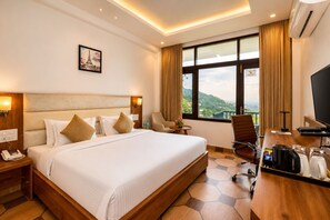 Une chambre d’hôtel avec un grand lit, un bureau avec une chaise, une télévision et une fenêtre donnant sur un beau paysage.