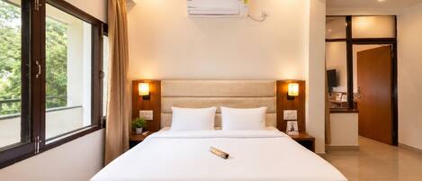 Habitación de hotel con una cama grande, aire acondicionado de pared y vistas a zonas verdes.