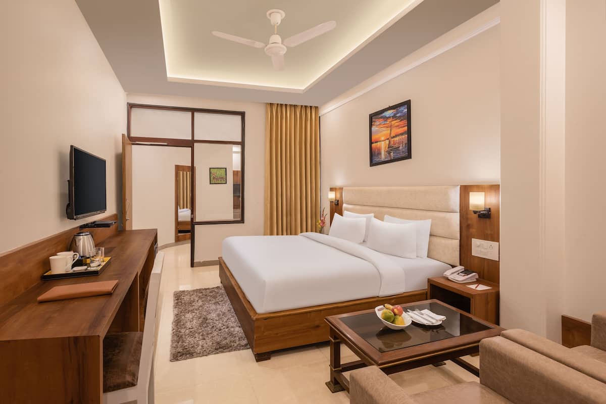 A hotel room with a bed, a desk, a television, a coffee maker, and a painting on the wall.