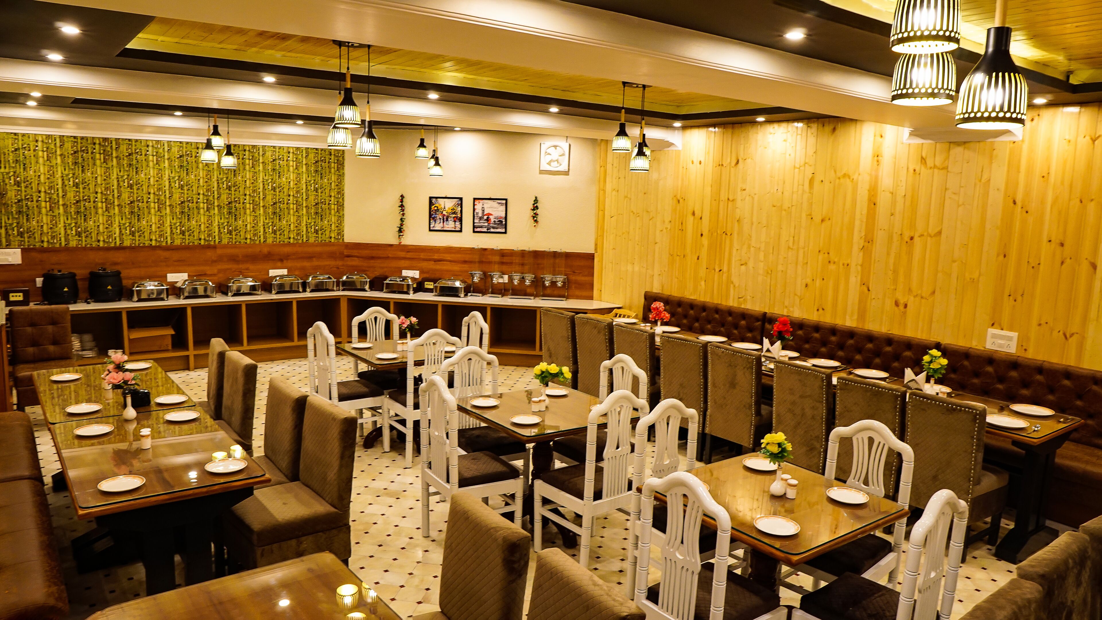 A restaurant with multiple dining tables and booths, a counter with food service equipment, and a variety of hanging lights.