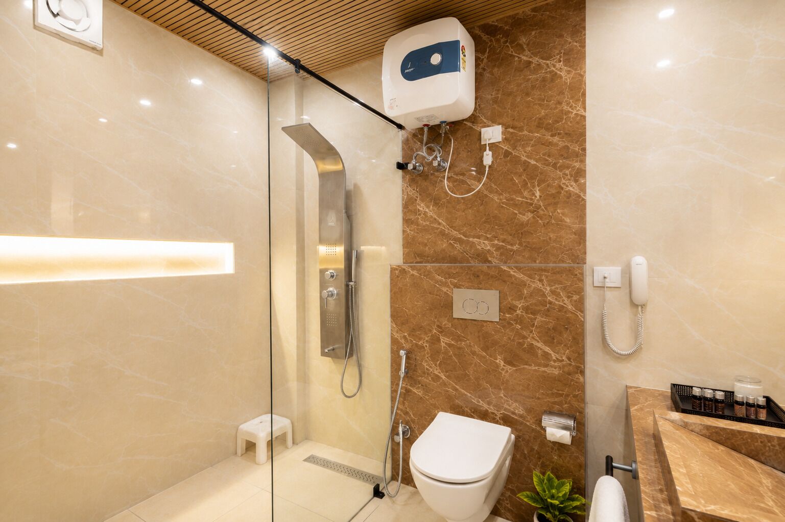 A modern bathroom with a glass-enclosed shower, a toilet, and a sink with a soap dispenser.