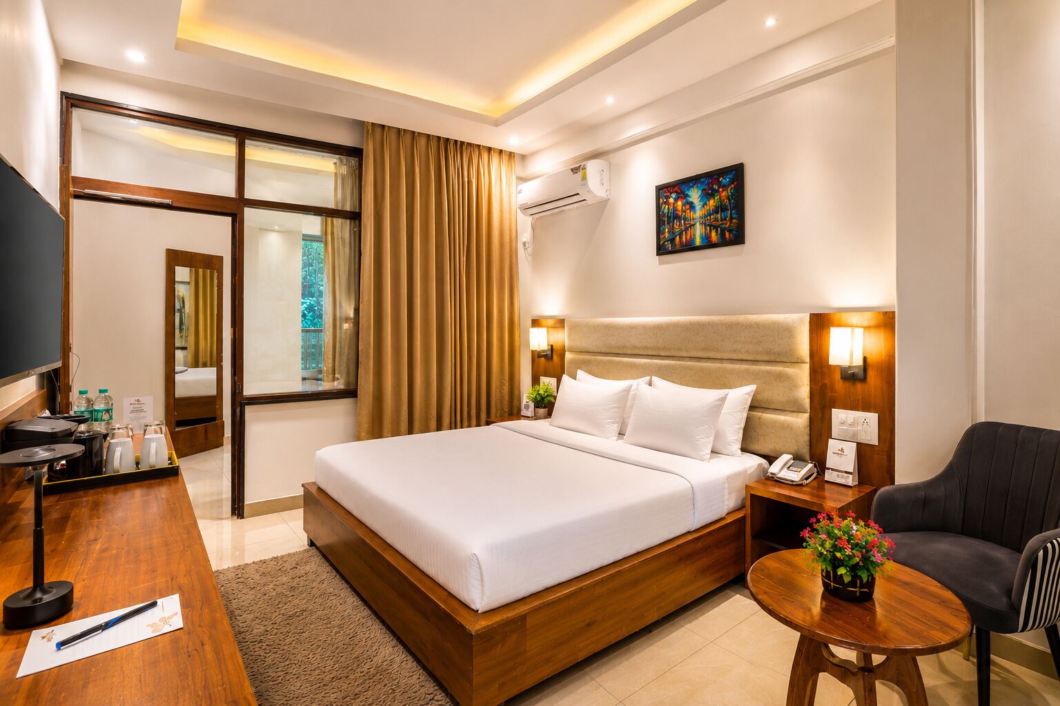 A hotel room with a bed, bedside table, chair, and a desk with a telephone.