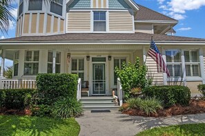 A two-story house with a front porch, a mailbox, and an American flag.
