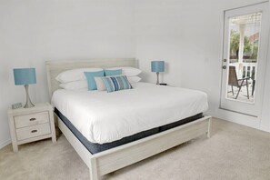A bedroom with a bed, bedside tables, lamps, and a door with blinds.