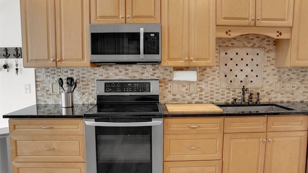 Una cocina con armarios de madera, un microondas, un horno y un lavabo.