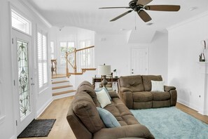 A spacious living room with a brown sofa, a recliner, and a blue rug.