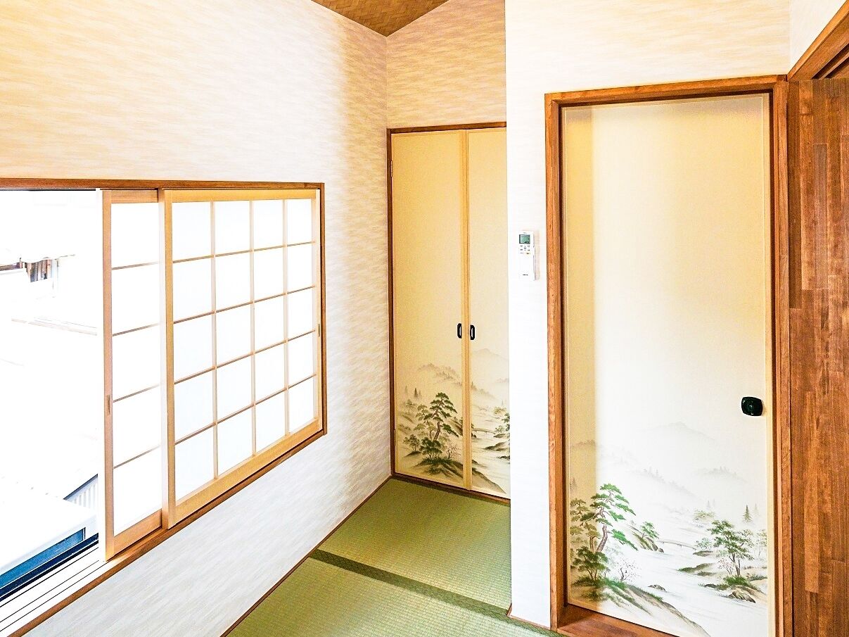 Una habitación japonesa tradicional con puertas correderas, suelo de tatami y un biombio shoji con una pintura de paisaje.