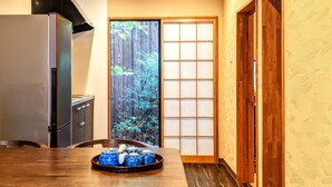 A traditional Japanese-style room with tatami flooring, a sliding door with a view of bamboo, and a table with a tray of blue ceramic cups. - INN Plus Toji Kindo (Kyoto)