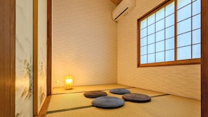 A tatami mat room with a shoji screen, tatami mats, a small table with a light, and a window with a grid pattern. - INN Plus Toji Kindo (Kyoto)