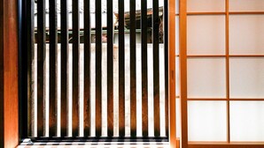 A traditional Japanese sliding door with vertical slats, a wooden frame, and a grid-patterned paper screen on the right. - INN Plus Toji Kindo (Kyoto)