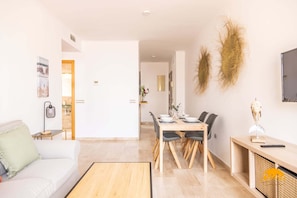 Un salon moderne comprenant un canapé, une table à manger, des chaises et un téléviseur.