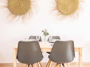 Un tavolo da pranzo con due sedie, un vaso con fiori e due decorazioni tessili appese al muro.