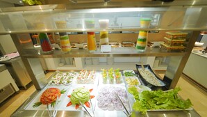 Un bufé con distintos alimentos, entre ellos ensaladas, frutas y verduras.