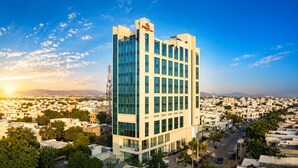 Un edificio moderno con un llamativo letrero 'PRID', rodeado de una zona residencial con calles visibles y áreas verdes.