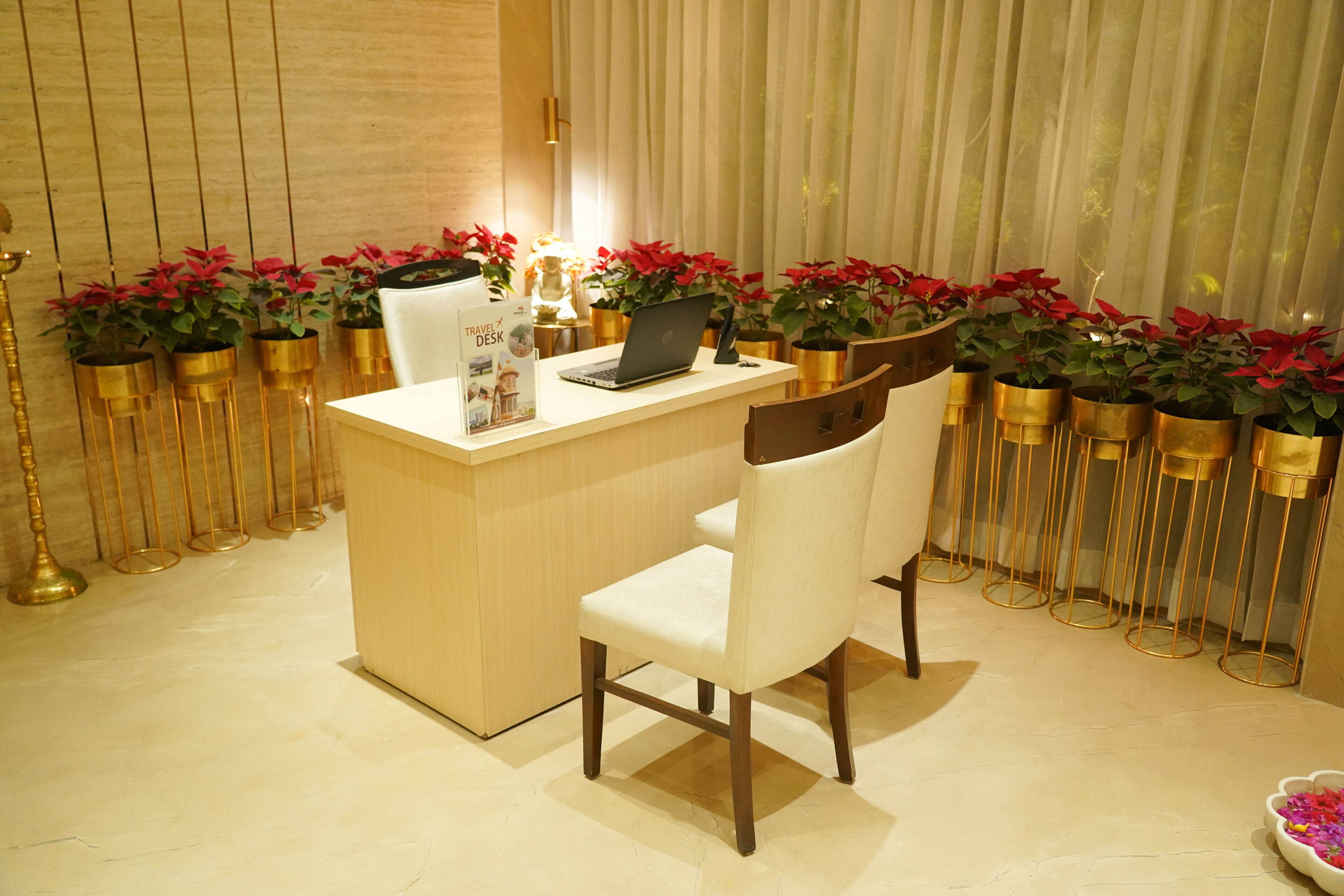 A reception desk with a laptop, a white chair, and a brochure titled "TRAVEL DESK".