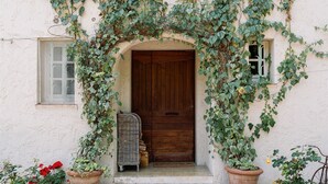 A rustic building with a wooden door, ivy-covered walls, and potted plants. - Heated pool, Outdoor cinema, Spa Terrace, Stroll to Shops, luxury equipped (Mougins)