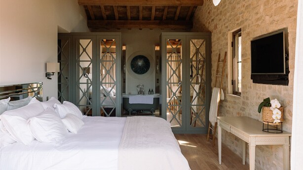 A bedroom with a large bed, a small desk with a mirror, a stone wall, and a wooden ceiling. - Heated pool, Outdoor cinema, Spa Terrace, Stroll to Shops, luxury equipped (Mougins)