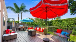 Una terraza con mobiliario exterior, incluyendo un sofá y sillas, y una parrilla.