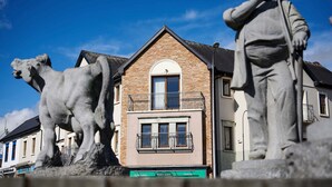 Un edificio con fachada de piedra, un balcón y un cartel que dice 'Audiólogos' y 'Optólogo'.