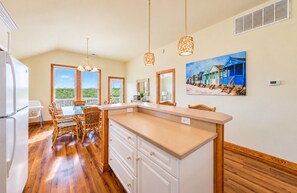 A kitchen with a large island, wooden flooring, and a dining area with a view.