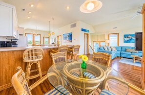 A spacious living area with a large blue sofa, wicker furniture, and a glass-top dining table.