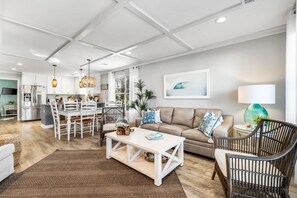 A modern living room with a dining area, a sofa, and a coffee table. - The Sandpiper Crystal Beach*Pool*FirePit*BeachSvc (Destin)