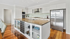 Eine moderne Küche mit weißen Schränken, einem Edelstahlkühlschrank und einer zentralen Kochinsel mit Spüle und Stauraum.