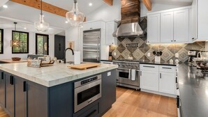 A modern kitchen with a large island, stainless steel appliances, and a patterned backsplash.