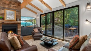 A spacious living room with leather sofas, a fireplace, and a large sliding glass door leading to an outdoor patio.