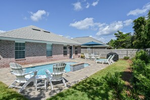 Un jardin avec une piscine, un espace salon extérieur et un coin barbecue.